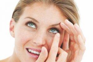 happy blonde woman putting in contacts in Wilmington